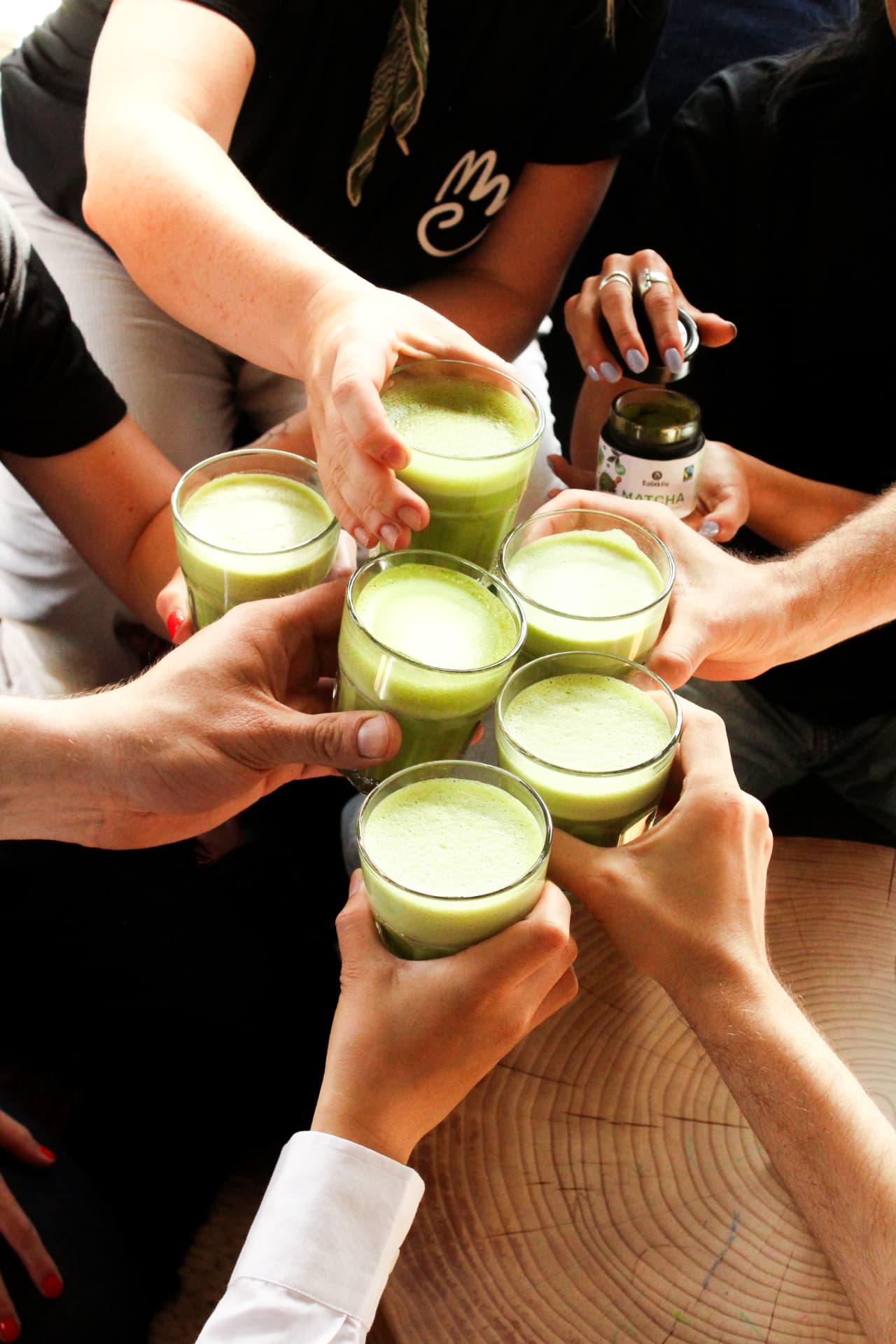 Matcha Getränke, Matcha Dose und Bambusbesen auf einem Holztisch
